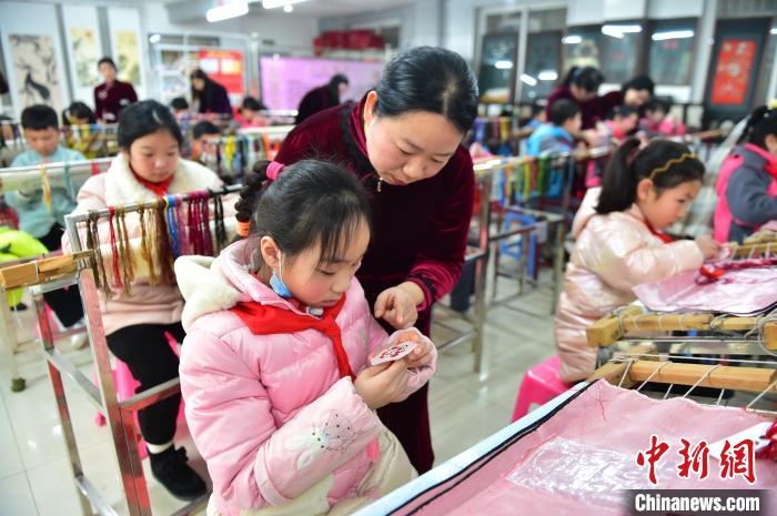 江西省級非遺豫章繡傳承人手把手指導小學生繡制2022年北京冬奧會吉祥物“冰墩墩”形象。　喻云亮 攝