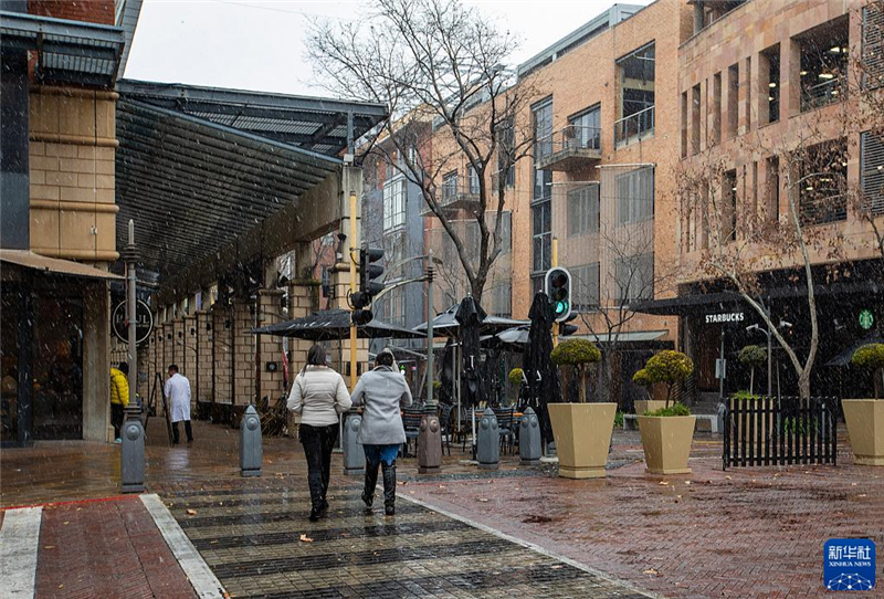 7月10日，在南非約翰內(nèi)斯堡一處商業(yè)區(qū)，人們在雪中行走。新華社記者 張譽(yù)東 攝