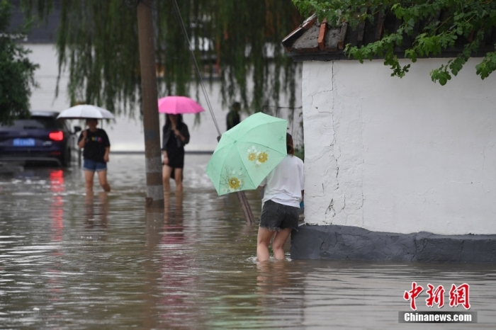 7月31日，市民行走在雨中的北京房山區(qū)瓦窯頭村。北京市氣象臺當日10時發(fā)布分區(qū)域暴雨紅色預警信號。北京市水文總站發(fā)布洪水紅色預警，預計當日12時至14時，房山區(qū)大石河流域將出現(xiàn)紅色預警標準洪水。<a target='_blank' href='/'><p  align=