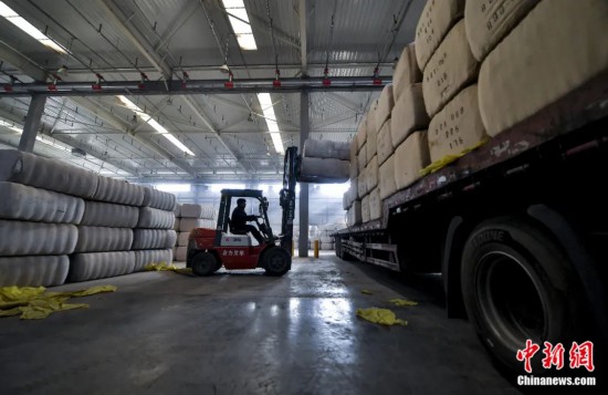 新疆喀什綜合保稅區(qū)，喀什啟路國際貿(mào)易有限公司的倉庫內(nèi)，工人正在裝載從塔吉克斯坦和烏茲別克斯坦進(jìn)口的棉花。劉新攝