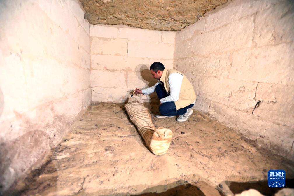 10月15日，在埃及明亞省考古現(xiàn)場(chǎng)，考古人員清理一座石鑿墓中的木乃伊。新華社發(fā)（艾哈邁德·戈馬攝）