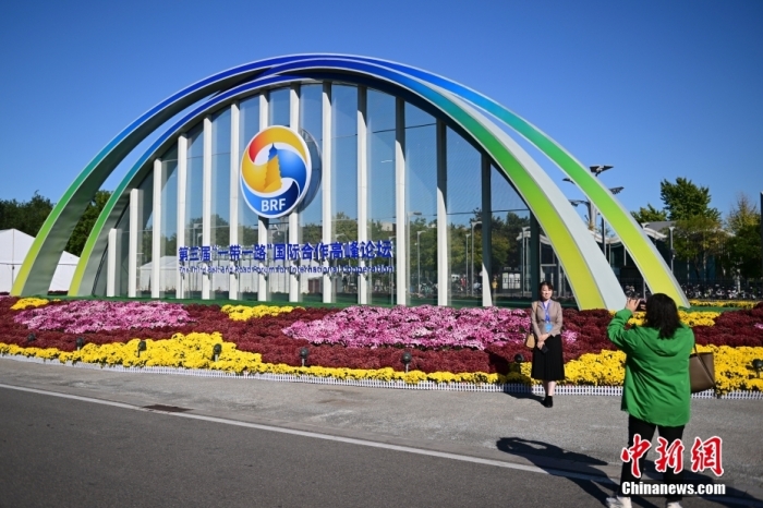 10月15日，北京，工作人員在國家會議中心外的第三屆“一帶一路”國際合作高峰論壇景觀布置前拍照留念。當日，位于國家會議中心的第三屆“一帶一路”國際合作高峰論壇新聞中心啟動試運行。據(jù)悉，第三屆“一帶一路”國際合作高峰論壇將于10月17日至18日在北京舉行。<a target='_blank' href='/'><p  align=