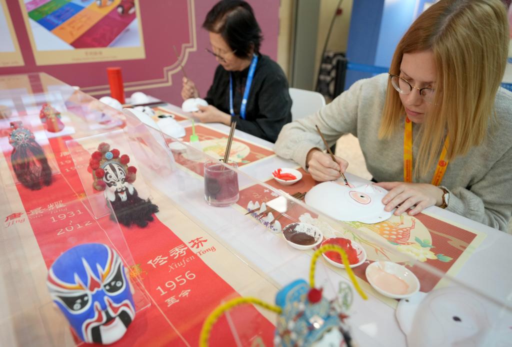 10月16日，在第三屆“一帶一路”國際合作高峰論壇新聞中心，來自比利時的記者（右）體驗畫京劇臉譜。新華社記者 王毓國 攝