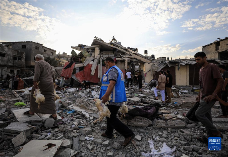 10月27日，在加沙地帶南部城市汗尤尼斯，人們經(jīng)過以軍襲擊后的房屋廢墟。
