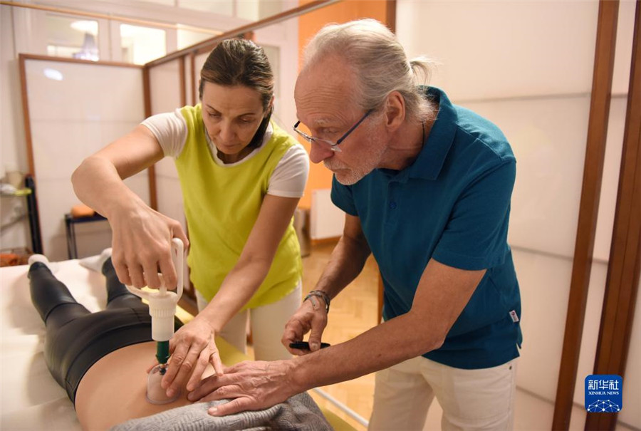 12月12日，在奧地利維也納，科格勒醫(yī)生（右）和助手在為病人進行拔罐治療。新華社記者 賀燦鈴 攝