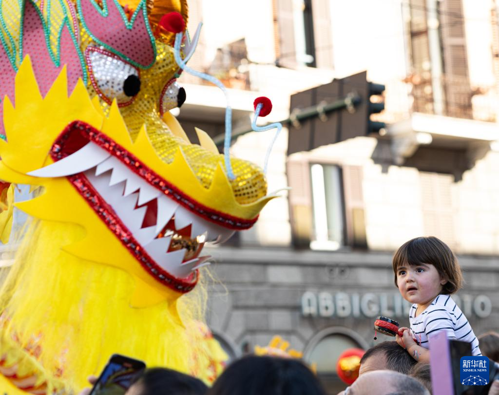 2月18日，在意大利羅馬，一名小朋友在彩妝巡游上觀看舞龍。新華社記者 李京 攝