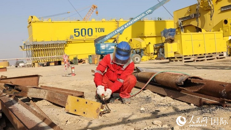 工人正在龍門吊吊裝現(xiàn)場切割金屬件。人民網(wǎng)記者管克江攝