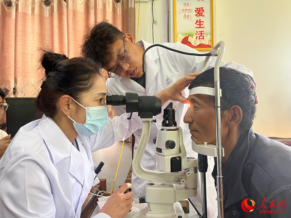 王紅英（左）和團隊成員為達熱村村民檢查眼睛。人民網(wǎng)記者 杜燕飛攝