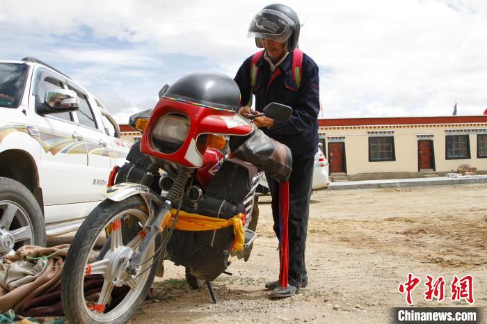 圖為白瑪準(zhǔn)備騎摩托車巡湖?！≮w朗 攝