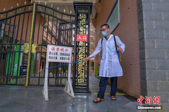 資料圖：海口經(jīng)濟(jì)學(xué)院的工作人員在學(xué)生宿舍樓入口消毒。 中新社記者 駱云飛 攝