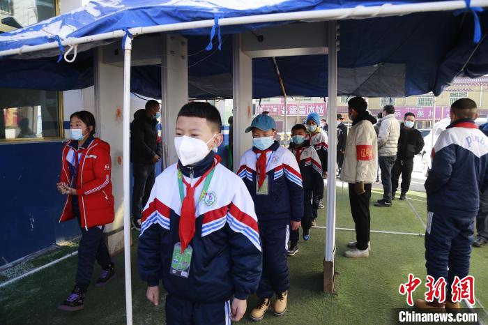 圖為學(xué)生測量體溫后進入校園?！●R銘言 攝