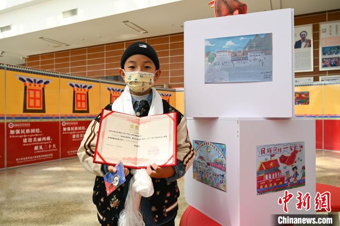圖為一名獲獎(jiǎng)學(xué)生與自己的繪畫作品合影?！≮w朗 攝