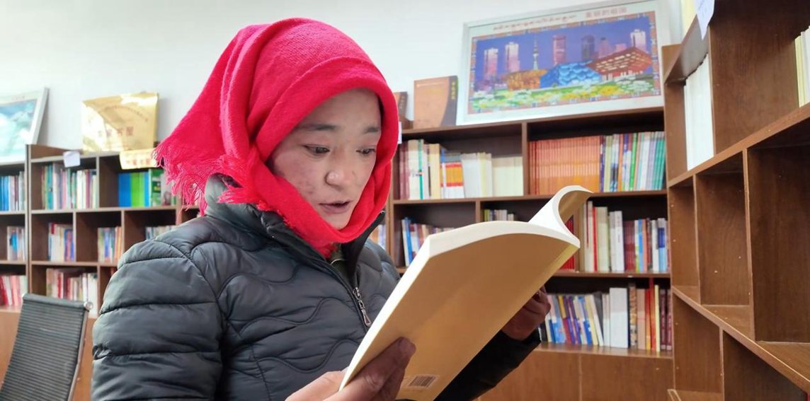 一名婦女正在認(rèn)真閱讀書籍。申扎縣融媒體中心供圖