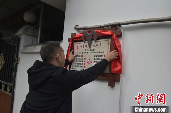 桂溪鎮(zhèn)渭溝村政府工作人員為“十星級文明戶”掛上牌匾?！钣?攝