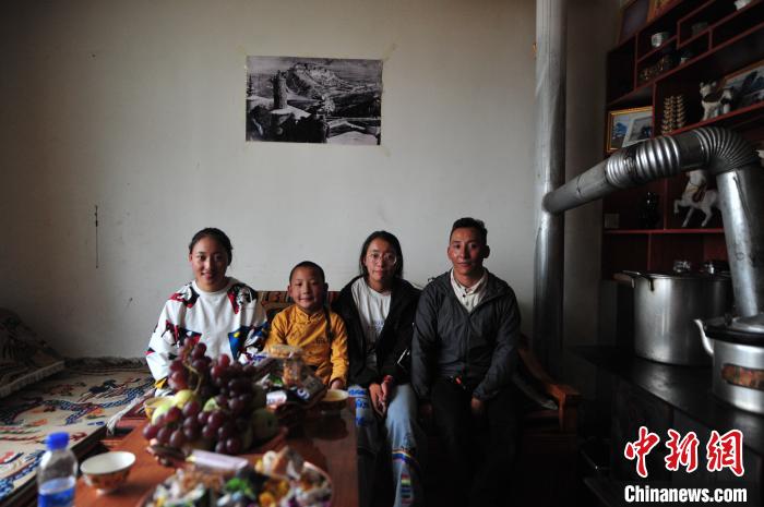 圖為8月12日，2018年7月從距那曲市色尼區(qū)城區(qū)那曲鎮(zhèn)90千米外的古露鎮(zhèn)當(dāng)桑村搬遷至城區(qū)的旦增(右一)與家人在80多平方米的新家合影(資料圖)。　張偉 攝