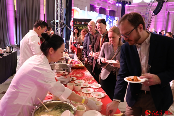 當(dāng)?shù)貢r間3月7日晚，華盛頓聯(lián)合車站廣場舉行駐美使團(tuán)“使館主廚挑戰(zhàn)賽”。圖為當(dāng)?shù)孛癖娫谥袊古_前體驗(yàn)中國美食。人民網(wǎng)記者 李志偉攝