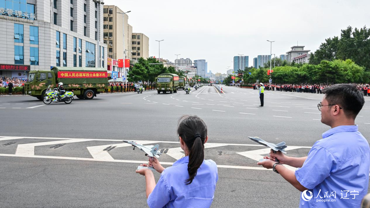 航空工業(yè)沈飛的青年技術(shù)人員拿著受閱戰(zhàn)機(jī)的模型迎接烈士遺骸。航空工業(yè)沈飛供圖