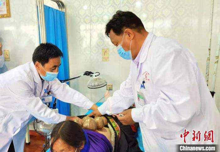 圖為看照加手把手帶徒弟加老(左一)進行拔罐療法。　張婧 攝