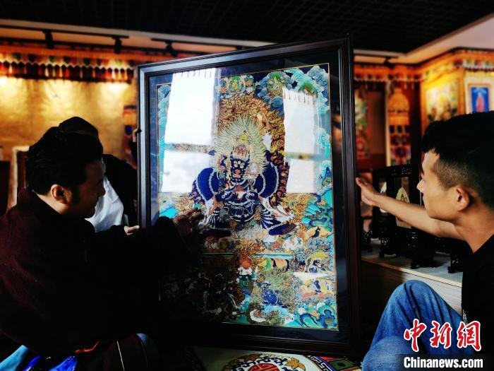 圖為久美尖措(左)與徒弟們展示唐卡作品。　張?zhí)砀?攝