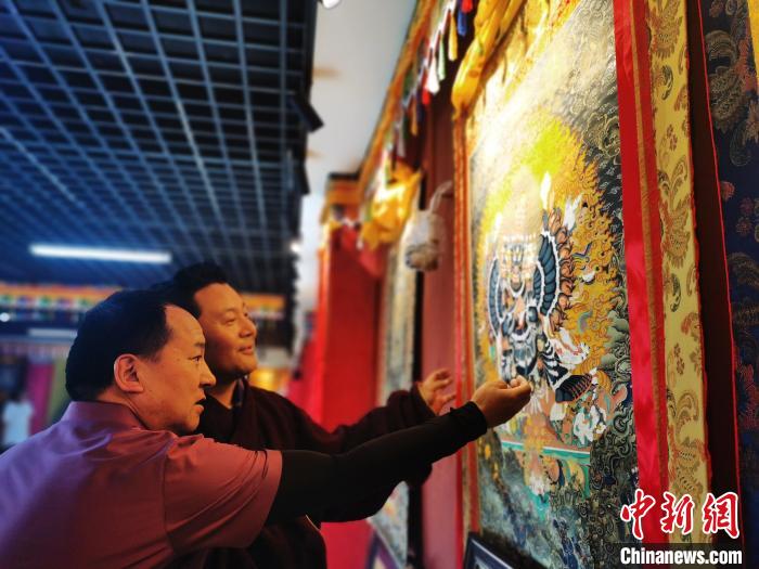 圖為久美尖措展示唐卡作品?！?zhí)砀?攝