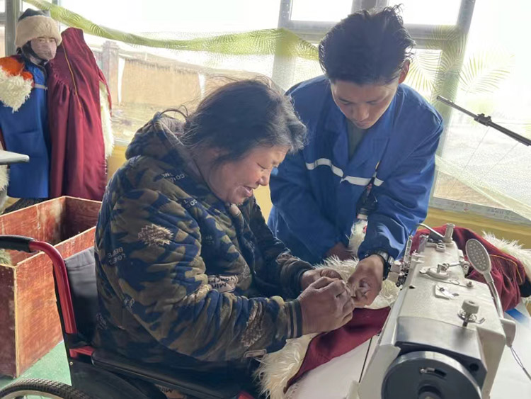 扎西奪爾登幫助殘疾員工裁剪。阿壩州文明辦供圖