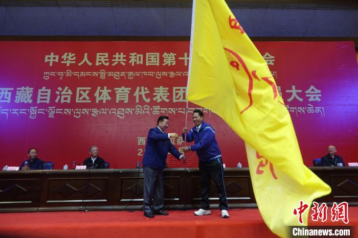 西藏自治區(qū)副主席甲熱·洛桑丹增授代表團(tuán)團(tuán)旗，西藏自治區(qū)體育局局長尼瑪次仁接旗?！∪轿木?攝