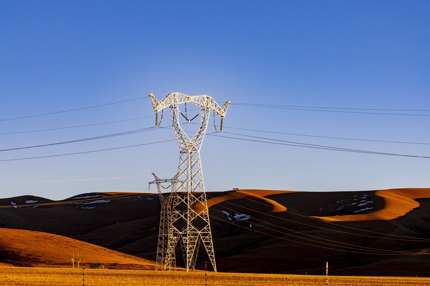 阿里地區(qū)的曠野上，電力鐵塔在夕陽下熠熠生輝。