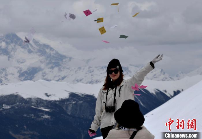 圖為5月14日，游客在西藏林芝色季拉山觀景臺拋灑“隆達”(風馬旗，藏族民眾的一種祈福方式)?！±盍?攝