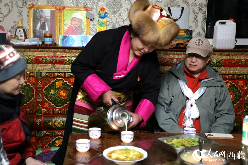 扎西曲登社區(qū)的居民在家中熱情招待遠道而來的游客。居民身著盛裝，為游客倒上熱騰騰的酥油茶，桌上擺放著切瑪與特色美食，賓主共話民族團結(jié)情誼。人民網(wǎng)記者 吳雨仁攝