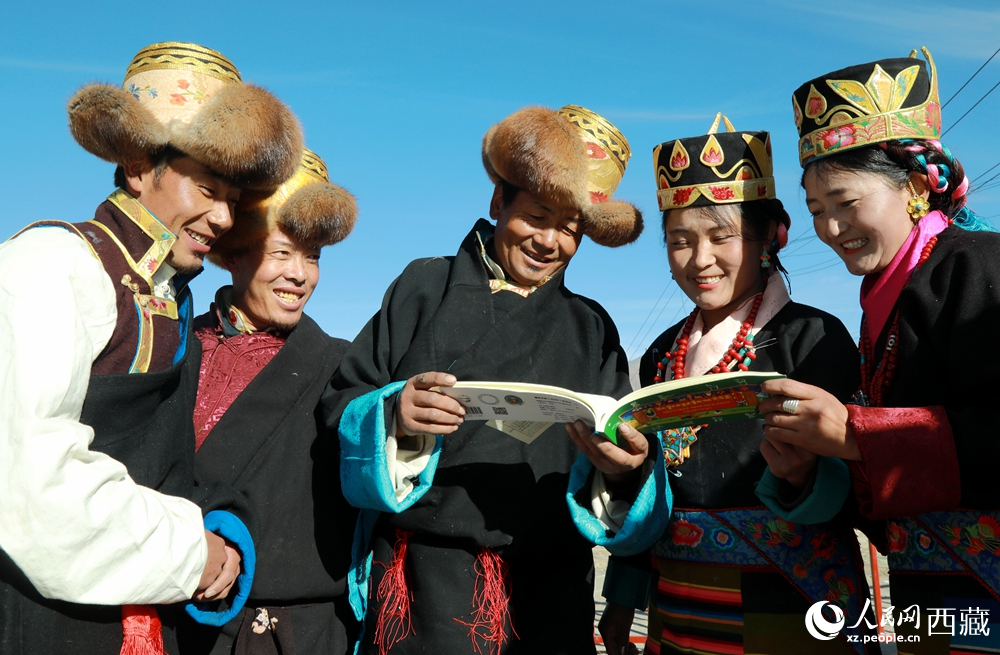 鄉(xiāng)親們身著民族盛裝，圍站在一起認(rèn)真翻看日歷，共話農(nóng)事安排與時(shí)節(jié)規(guī)律，笑容洋溢傳遞豐收期盼。人民網(wǎng)記者 吳雨仁攝