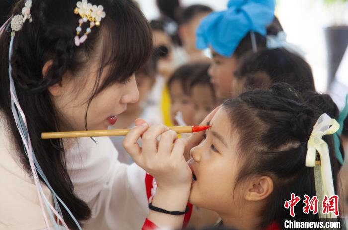 圖為老師在孩子們額頭上點(diǎn)上雄黃，驅(qū)邪辟禍?！《^生 攝